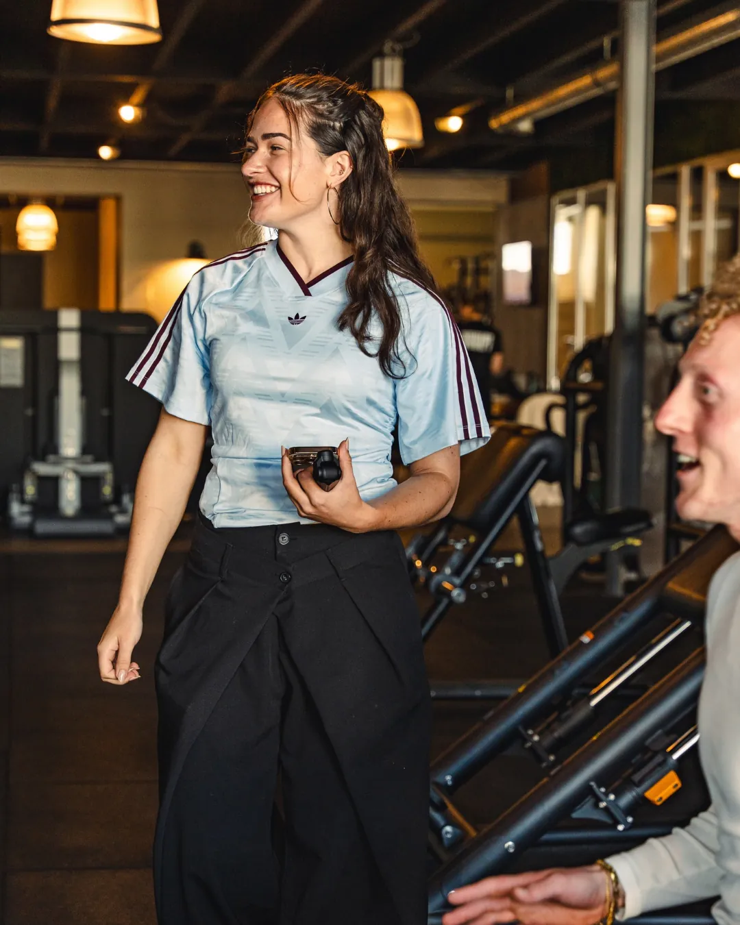 Karin Polstra loopt met haar telefoon door de sportschool